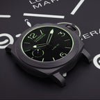 A Luminor Marina watch by Panerai, featuring a matte black case and a black dial with glowing green indices, displayed on a dark background with white clock markings.